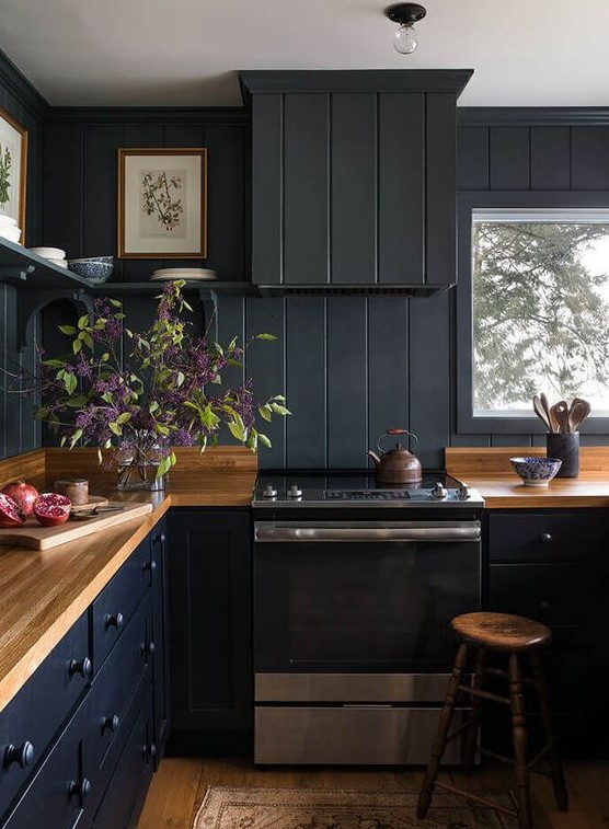A black farmhouse kitchen done with beadboard, light colored wooden countertops and stools plus open shelving