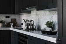 a black framhouse kitchen with white marble countertops and a backsplash is a chic and stylish idea