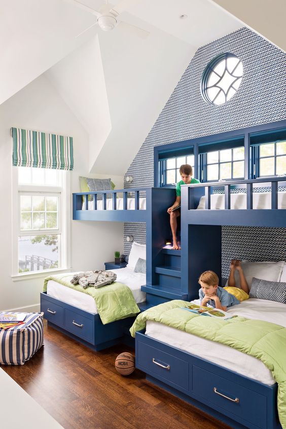 A bright kids' room with built in navy bunk beds, white and green bedding, a ladder, an accent wall and striped pieces