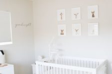 a calming neutral nursery with a gallery wall of animal portraits, a white IKEA Sundvik crib, a faux fur rug and some whites and off-whites