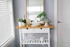 a chic IKEA Forhoja cart done with marble contact paper, with a wooden countertop as a small home bar