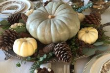 a chic fall centerpiece of a vintage tray, foliage, pinecones, white pumpkin and a giant heirloom one