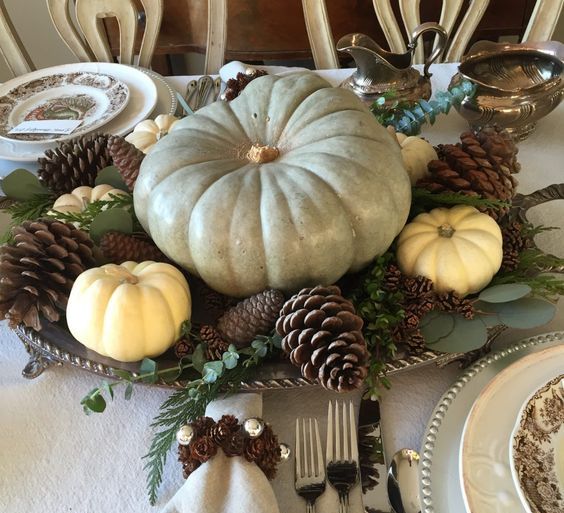 a chic fall centerpiece of a vintage tray, foliage, pinecones, white pumpkin and a giant heirloom one
