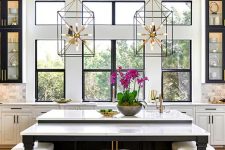 a chic glam kitchen with white and black cabinets, white marble tiles, cool sunburst chandeliers and gold and white stools