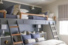 a chic kids’ room with built-in bunk beds, navy and grey bedding, ladders, elegant nightstands and pendant lamps