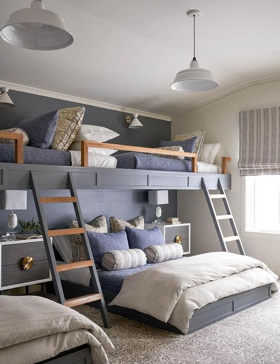 A chic kids' room with built in bunk beds, navy and grey bedding, ladders, elegant nightstands and pendant lamps