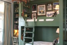 a chic kids’ room with green walls and a built-in bunk bed, a ladder, a vintage chandelier and a built-in desk space with shelves