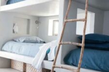 a coastal space with white built-in bunk beds, with blue and navy bedding, with a ladder and navy rugs is a stylish space with love to the sea