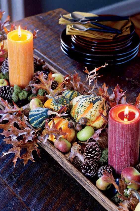 a colorful harvest centerpiece of pinecones, apples, leaves, moss, gourds and colorful candles