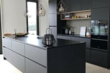 a contemporary black kitchen with sleek cabinets, an oversized kitchen island and catchy wire lamps