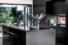a contemporary moody kitchen with sleek black cabinetry, a kitchen island, a glazed wall with an entrance to a courtyard