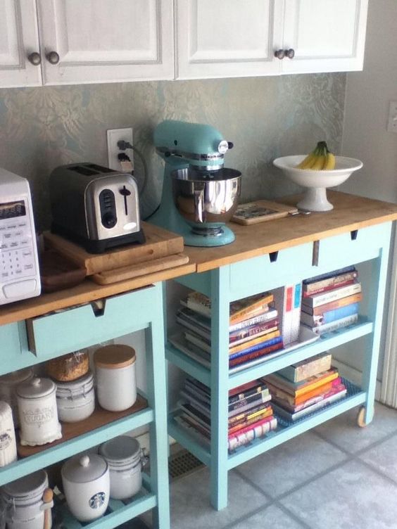 A cooking kitchen area made of two IKEA Forhoja carts in light blue, with wooden countertops is very space saving