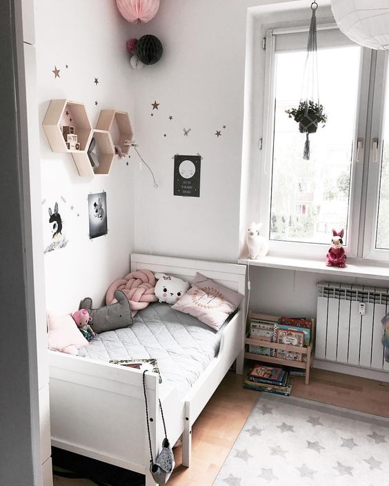 a cozy and soothing kid's room done in white, black and pink, with a white IKEA Sundvik bed, hex shelves, paper lanterns and a potted plant