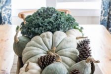 a cozy harvest centerpiece of a dough bowl with hirloom pumpkins and gourds, pinecones and fresh veggies