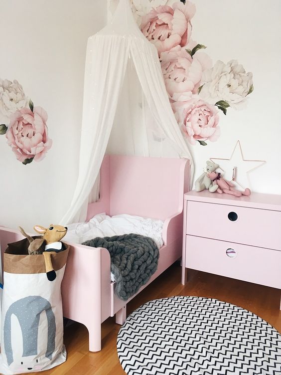 a delicate girl's bedroom with handpainted florals, a pink Sundvik bed, a printed rug, a canopy and a storage bag