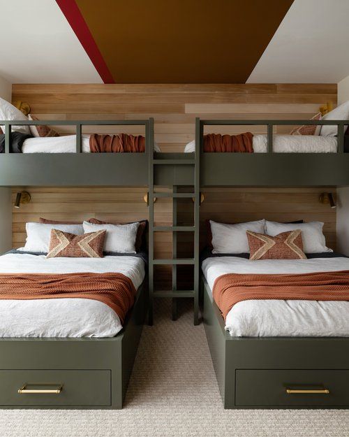 a farmhouse kids' room with a wood accent wall, dark green bunk beds, neutral and bold bedding