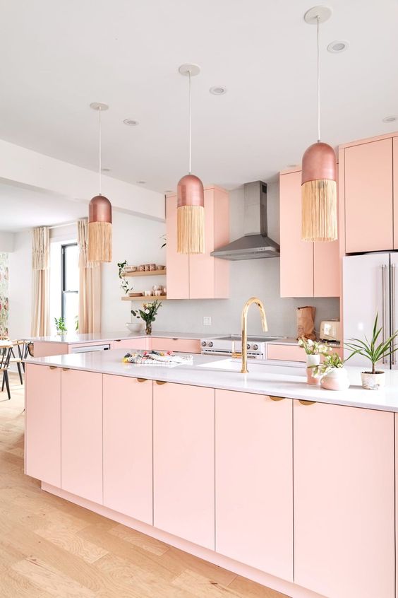 a feminine glam kitchen with pink cabinets, a grey backsplash and white countertops, dusty pink pendant lamps with fringe