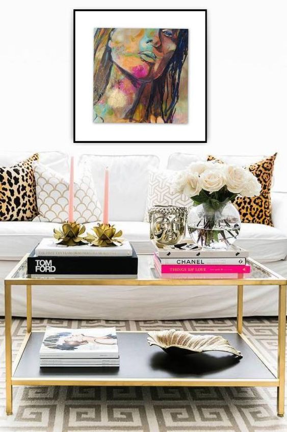 a glam black and gold coffee table with stacks of books, pink candles in floral candle holders, white blooms in a clear vase