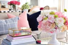 a glam gold and blue coffee table with a blue bowl, a stack of books, bright blooms in a white vase