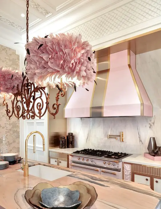 a glam kitchen with white cabients, a pink cooker and a matching hood, brass and copper detailing, a pink petal lamp is wow