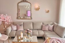 a glam living room with dove grey walls and a matching sectional sofa, pink pillows and blankets, pink blooms, poufs and chairs and some mirrors