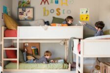 a grey kids’ room with three bunk beds, ladders, a space for hanging out, crate bookshelves and bright decor