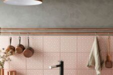 a grey kitchen with black cabinetry and a pink printed tile backsplash, a copper pendant lamp and copper pipes