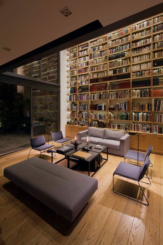 a large double-height modern library with lights, contemporary furniture and much light for reading