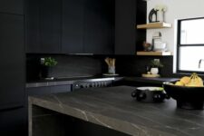 a matte black kitchen with a black marble backsplash and brown marble countertops, open shelves and some potted plants