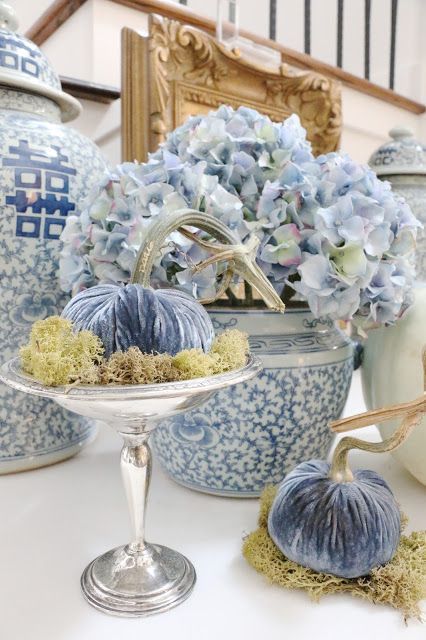a mini blue velvet pumpkin with moss placed on a chic vintage stand brings elegance and chic to the space