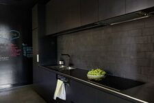 a minimalist black kitchen with sleek metal cabinets, a brick backsplash and a chalkboard wall looks wow