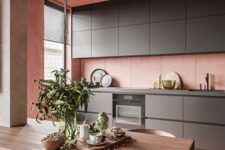 a minimalist kitchen in pink, with sleek graphite grey cabinetry, a concrete ceiling and a small dining space