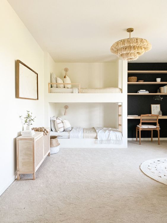 a modern boho kids' room with a built-in bunk bed, a black accent wall with built-in shelves and a desk, a dresser and a chair