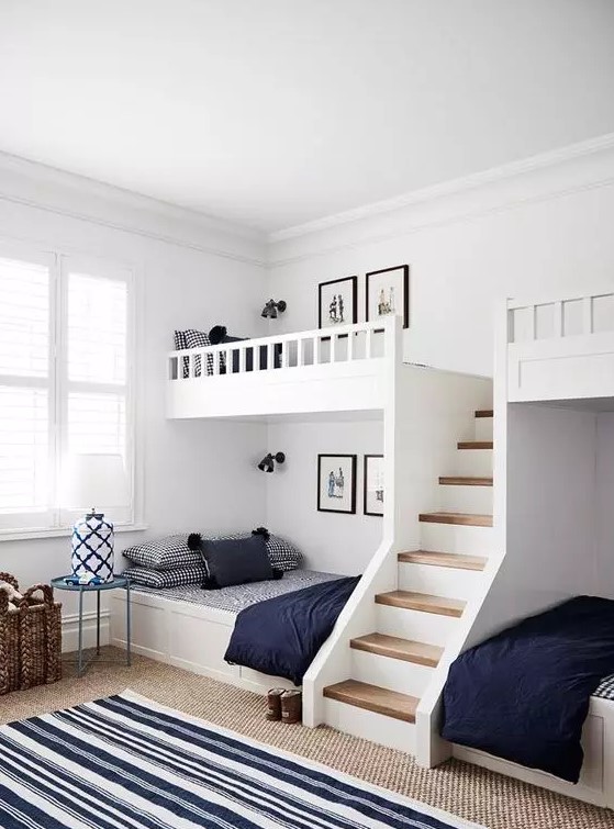 A modern farmhouse kids' room with built in bunk beds, navy and white bedding, layered rugs and side tables and baskets