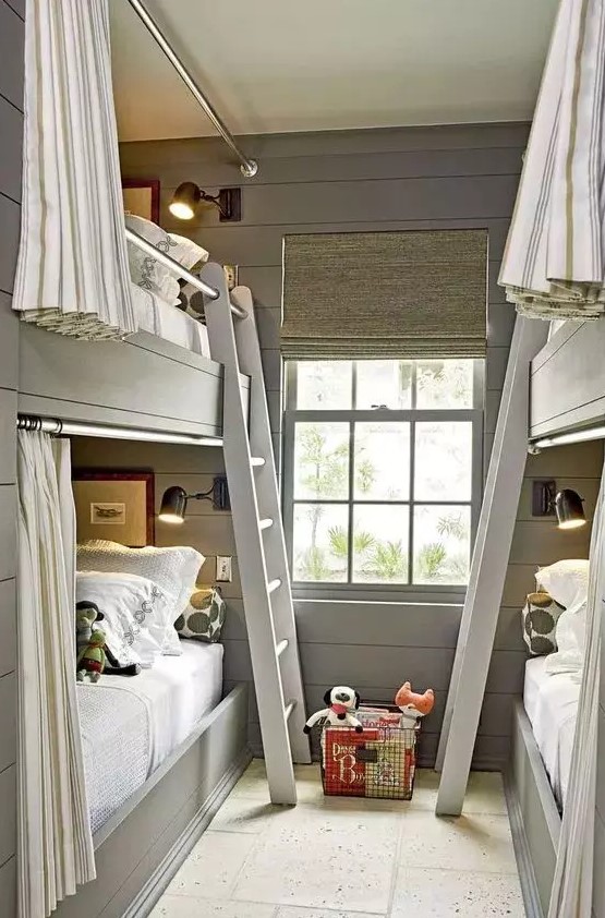 A modern grey kids' room with built in bunk beds, neutral and grey bedding, ladders and striped curtains plus black sconces