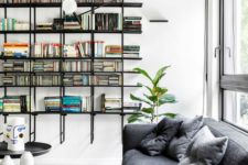 a modern home library with a floating black bookshelf unit and some contemporary furniture