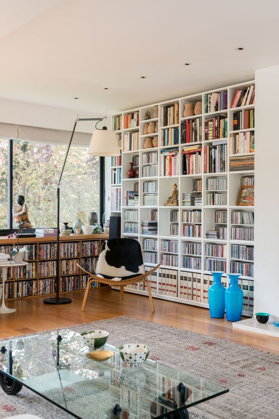 A modern home library with a large bookcase and a built in window unit plus a cowhide chair