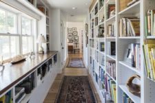 a modern home library with a large shelving unit that doubles as a space divider and a shelving windowsill unit