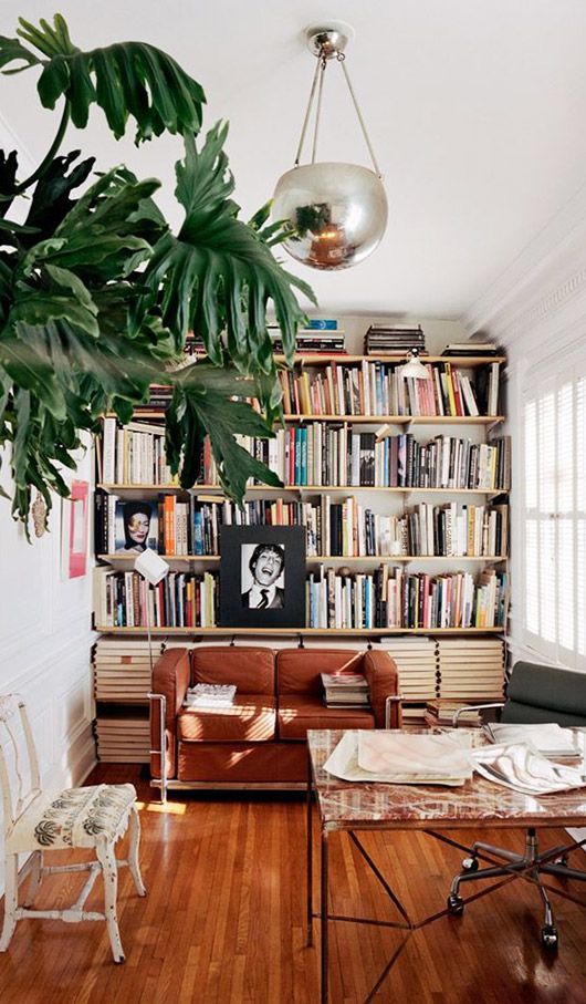 a modern home library with floating shelves, a small leather sofa and some comfy furniture and photos