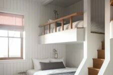 a modern kids’ room with white shiplap walls, built-in bunk beds with printed bedding, a gold star-shaped pendant lamp and a ladder