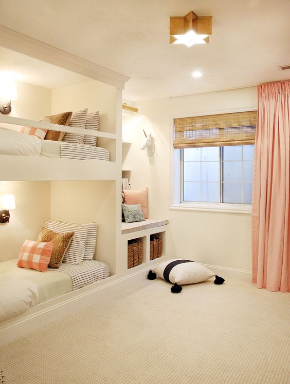 A modern white kids' bedroom with built in bunk beds and neutral and printed bedding, a built ins eat and a window with blinds