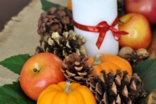 a natural fall centerpiece of a dough bowl, foliage, pinecones, nuts, acorns, apples, pumpkins and candles