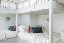 a neutral coastal kids’ room with built-in bunk beds, neutral bedding, a built-in ladder and seaside-inspired sconces