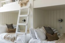 a neutral farmhouse kids’ bedroom with shiplap walls, built-in bunk beds, neutral bedding and a ladder plus wall sconces