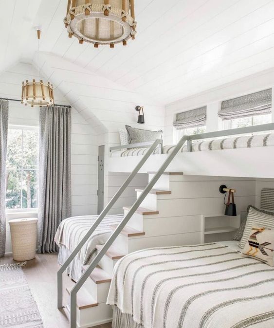 a neutral farmhouse kids' room with shiplap walls and a ceiling, bunk beds, a built-in ladder, rope chandeliers and neutral bedding