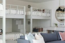 a neutral kids’ bedroom with built-in bunk beds and a ladder, neutral bedding, a grey sofa and pillows, a console table