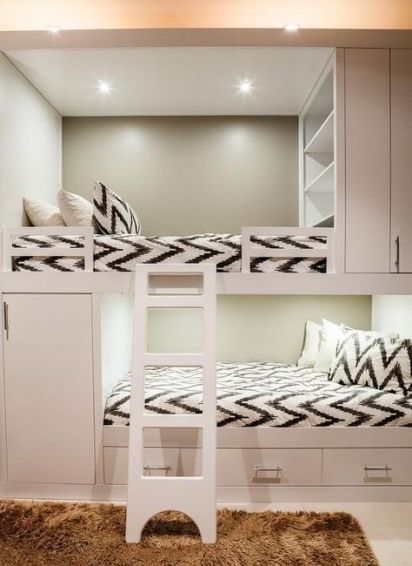 A neutral kids' room with built in bunk beds, printed bedding, built in shelves, a ladder and drawers for storage