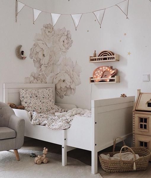 a neutral romantic kid's room with handpainted florals, a white Sundvik bed, a banner, a playhouse and baskets