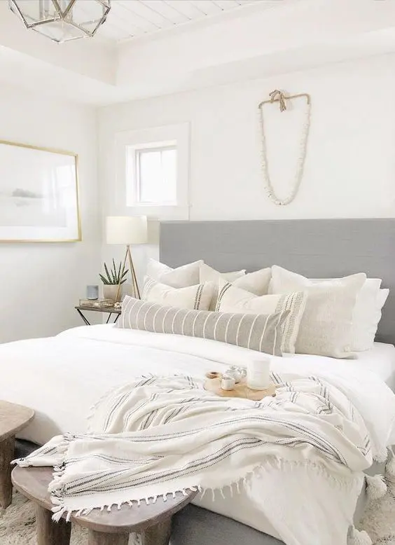 a neutral small bedroom looks larger cause of an extended headboard, a neutral color scheme and enough light