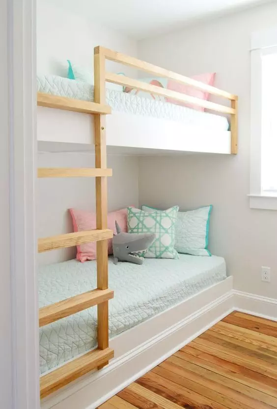 a pretty and cozy kids' room with white built-in bunk beds, pastel bedding and toys is a cozy space to sleep in